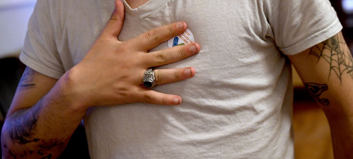 Austin Snell, 23, presses the sticker to his shirt after getting vaccinated at Fairfield Community Center on Friday, May 14, 2021.  (Kathy Plonka/The Spokesman-Review)