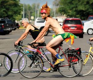 Two of the hundreds of bicyclists who showed up in a variety of dress and undress ride the route of the “Bare as You Dare” naked bike ride through downtown Missoula on Aug. 24, 2014. (Kurt Wilson / Missoulian)