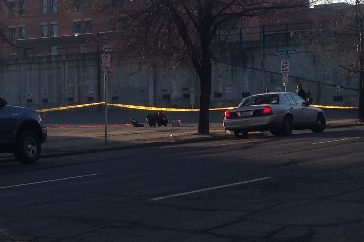 Detectives investigate the scene of a shooting in a parking lot at First Avenue and Monroe Street Monday morning.