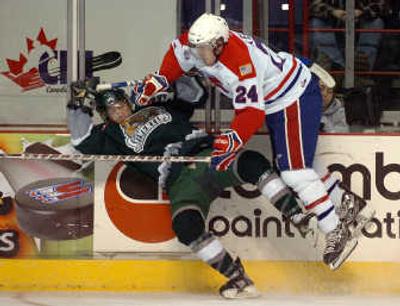 
Everett's Taylor Ellington, left, takes a hard check from Spokane's Curtis Kelner during the second period Wednesday at the Arena. 
 (Jesse Tinsley / The Spokesman-Review)