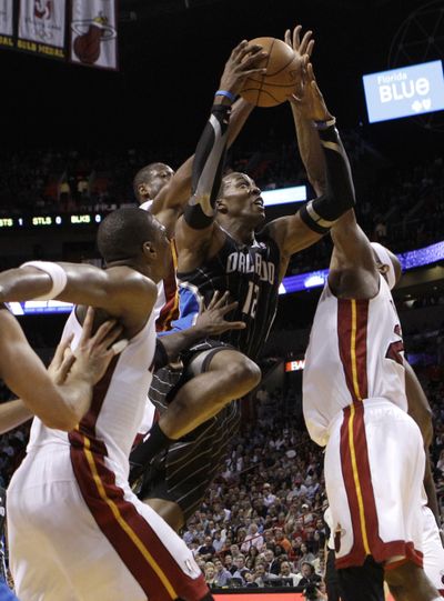 Orlando Magic's Dwight Howard (12) attacks the rim against Miami Heat's Erick Dampier, right, and Chris Bosh, left. (Associated Press)
