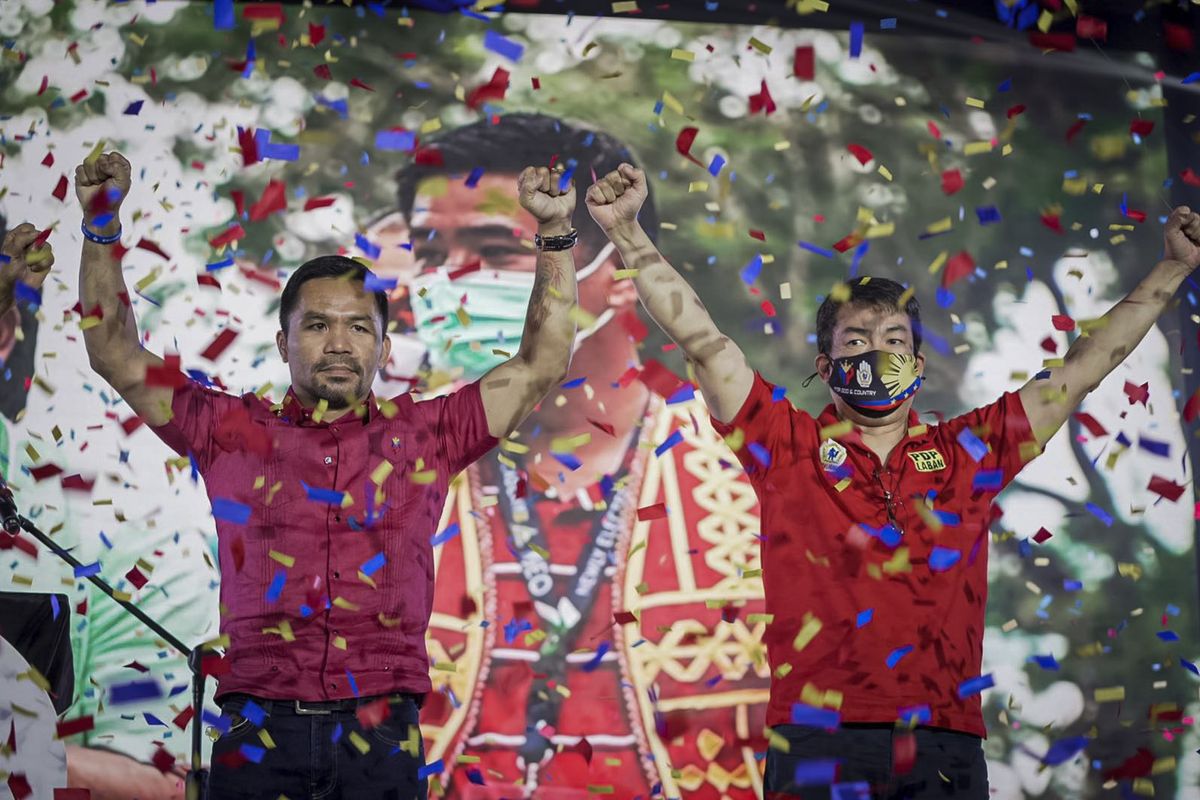 In this photo provided by the Manny Pacquiao MediaComms, Senator Manny Pacquiao, left, raises his hands during a national convention of his PDP-Laban party in Quezon city, Philippines on Sunday Sept. 19, 2021. Philippine boxing icon and senator Manny Pacquiao says he will run for president in the 2022 elections.  (HONS)