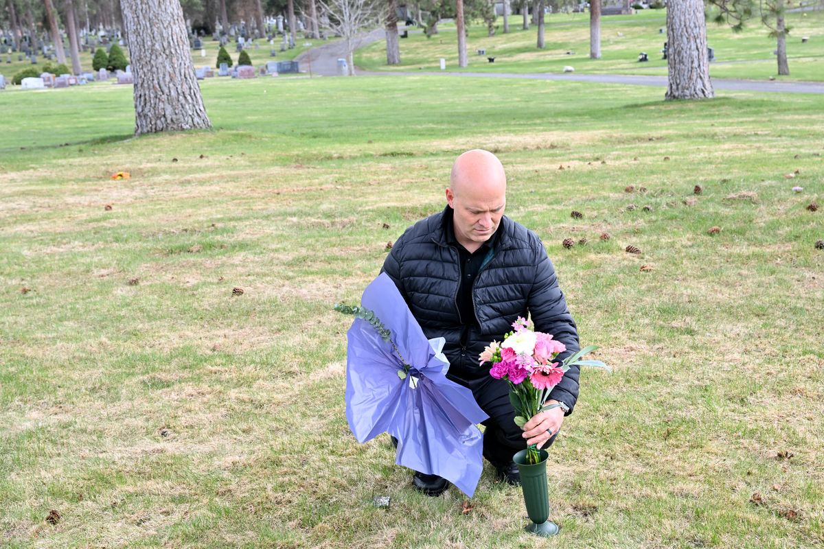 Spokane Police Sgt. Zac Storment places flowers on the unmarked grave of Ruth Belle Waymire on Friday, April 21, 2023, at Fairmont Memorial Park in Spokane, Wash. Waymire was identified through genetic geneaology in March. For 40 years, officials struggled to identify her dubbing her "Millie" and burying her in Fairmont Memorial Park under that name.  (Tyler Tjomsland/The Spokesman-Review)