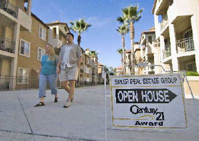 
Jason and Laura Bennett walk past an open house sign advertising their condominium in San Diego.  They've had to slash the top range of their asking price by $10,000 to keep up with other sellers in their complex. 
 (Associated Press / The Spokesman-Review)