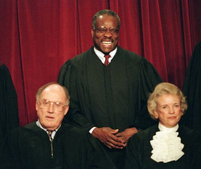 Associate Supreme Court Justice Clarence Thomas, center, laughs while posing with other members for a portrait at the court in Washington, D.C., Nov. 10, 1994. Seated in the front row are, Supreme Court Chief Justice William Rehnquist, left, and Associate Justice Sandra Day O’Connor. (J. SCOTT APPLEWHITE / Associated Press)