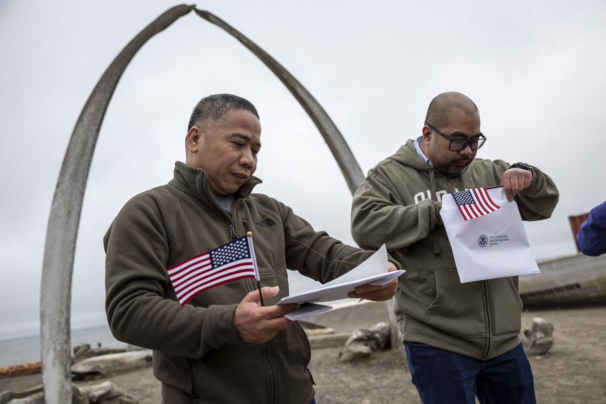 New American citizens check their citizenship certificates following a naturalization ceremony held in front of the “Gateway to the Arctic” whale bone sculpture on Aug. 10, 2023, in Utqiagvik, Alaska.  (John Moore)