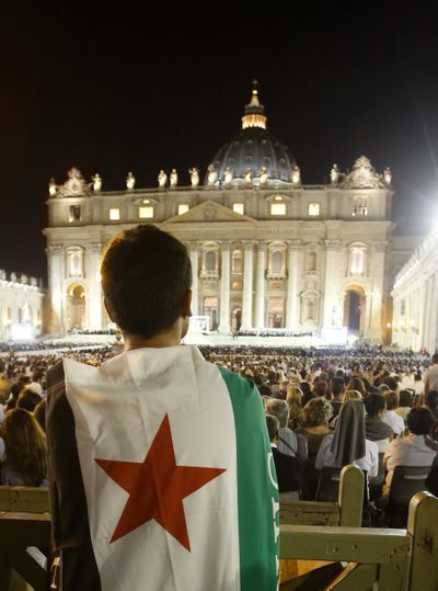 A man wearing a Syrian flag prays during a vigil for peace attended by Pope Francis in St. Peter’s Square at the Vatican on Saturday. Tens of thousands of people massed for the four-hour-long vigil. (Associated Press)