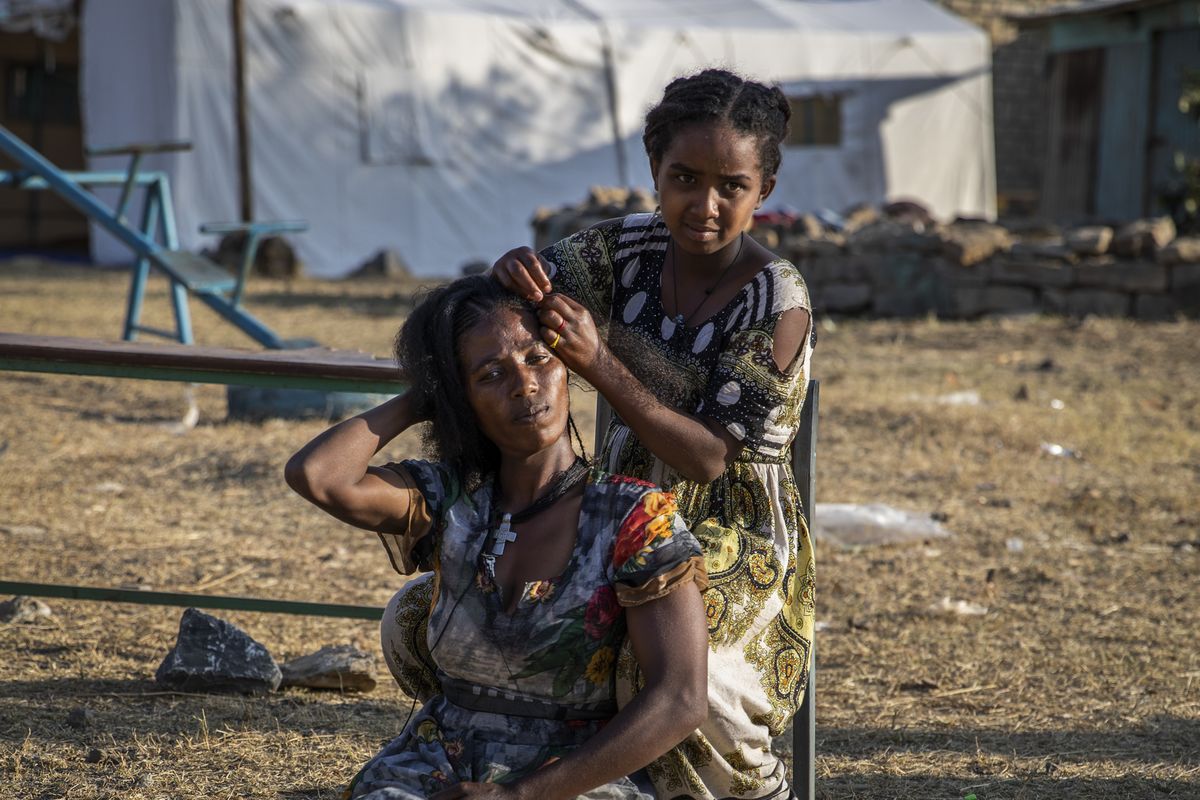 Almaz, 12, braids the hair of Zinabu at a center for people displaced by the recent conflict currently housing more than 3000 including 494 children under 5 years old, located in Meseret Primary School in Mekele, the capital of the Tigray region of northern Ethiopia Monday, Feb. 22, 2021.  (Zerihun Sewunet)