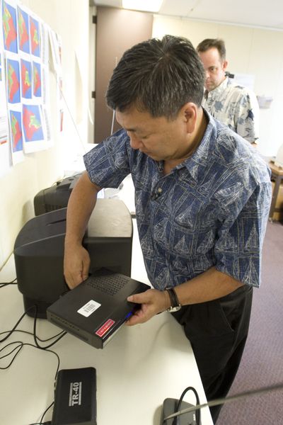 Lyle Ishida connects a digital converter to a TV at the Federal Communications Commission office in Honolulu Jan. 15.  (Associated Press / The Spokesman-Review)
