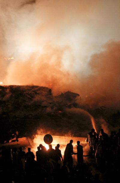 Pakistani volunteers and firefighters struggle to extinguish a fire at the site of a cargo plane crash in Karachi, Pakistan, before dawn today. (Associated Press)