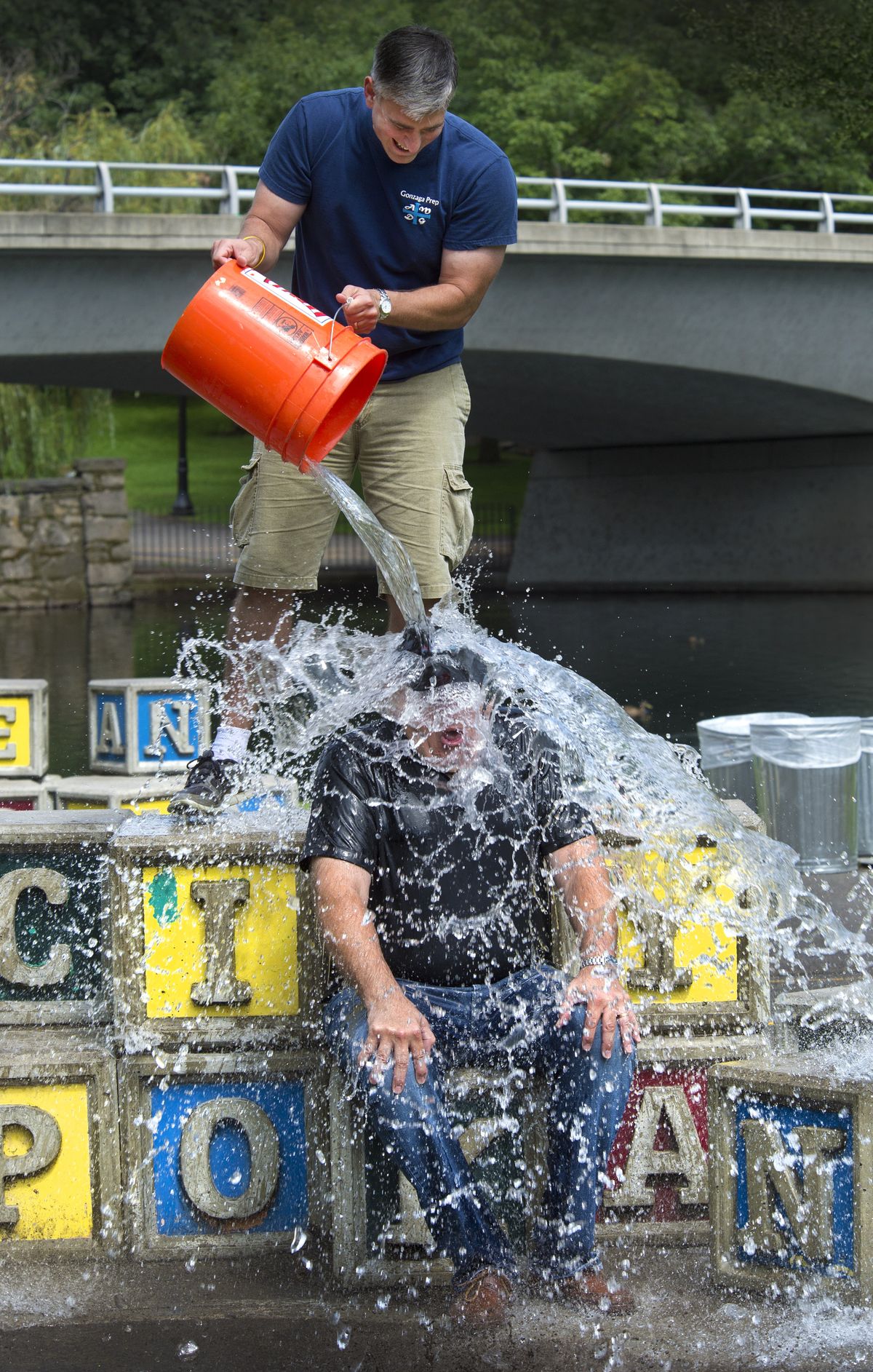State Sen. Michael Baumgartner pours a bucket of ice and river water over Doug Clark on Friday in Riverfront Park. Baumgartner challenged Clark to take the ALS Ice Bucket Challenge. (Dan Pelle)