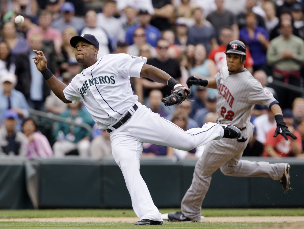 Adrian Beltre loses his grip on the ball on a ninth-inning infield single by Brian Buscher as Twins’ Carlos Gomez, right, reaches third base. (Associated Press / The Spokesman-Review)