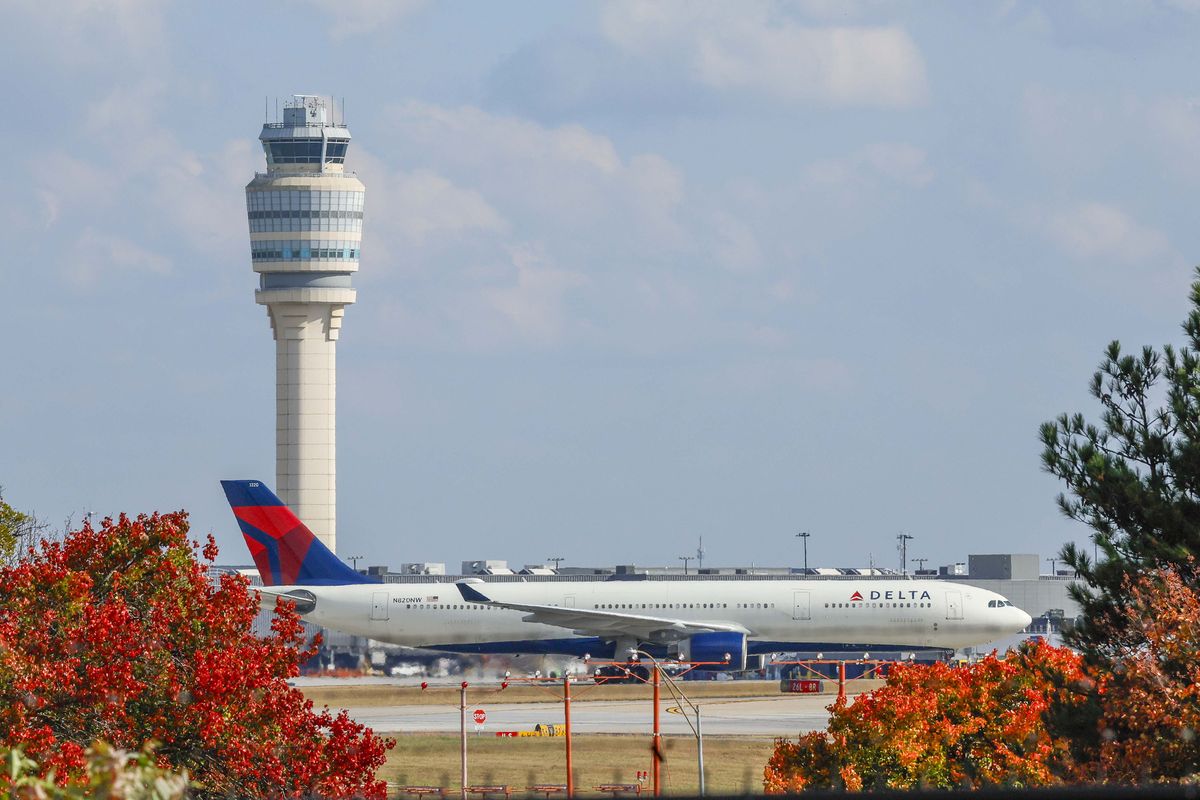 A Delta Air Lines plane passes by the Control Tower at Hartsfield-Jackson Atlanta International Airport on Sunday, Nov. 9, 2025. Transportation Secretary Sean Duffy warned on Friday that flight reductions might continue to increase if the government shutdown persists.   (MIguel Martinez/Atlanta Journal-Constitution/TNS)