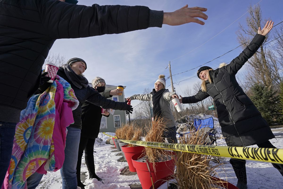 Canadians Stephanie Frizzell, far right, and her daughter, Shelby Dubois, second from right, move in for a big air hug with their American relatives, Christian Gervais, far left, Sherie Frizzell, second from left, and Caitlin Davis, third from left, after a visit at the U.S.-Canadian border of Stanstead, Quebec, and Derby Line, Vermont, on Dec. 19, 2020. Since shortly after the border closed in March 2020, people from both countries traveled to Derby Line and Stanstead to hold impromptu family reunions from their own side of the border on a residential street. It’s high summer along the border between the United States and Canada and people on both sides are wondering when the two governments will ease border-crossing restrictions.  (Elise Amendola)