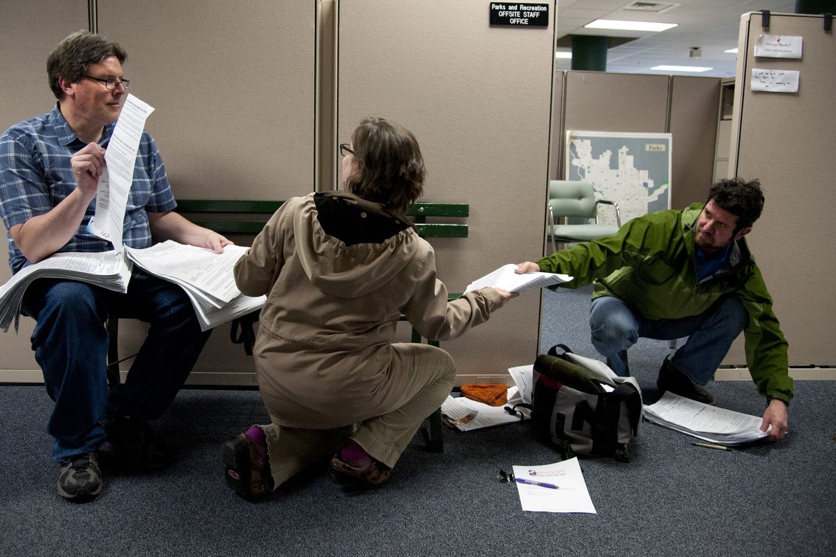 Brad Read, Suzanne Schreiner and Kai Huschke organize signed petitions on the fifth floor of Spokane City Hall to submit to the Spokane city clerk’s office in order to place their Community Bill of Rights initiative on the November ballot. (Dan Pelle)