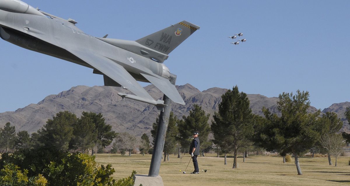 A golfer on the tee box of the first hole of the Falcon nine stops to watch as Air Force Thunderbird F16s – like the mounted statue in the foreground – scream at treetop level over the Nellis Air Force Base golf course. (Christopher Anderson)