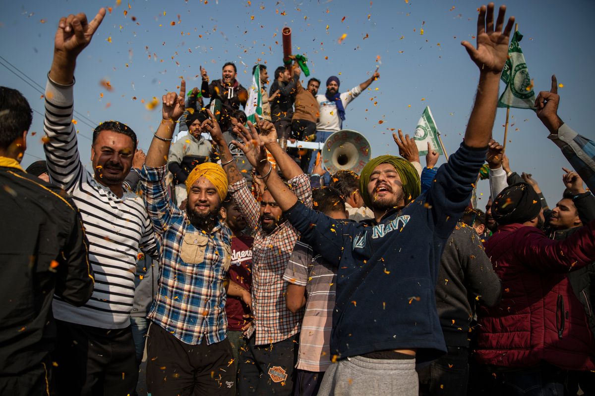 Indian farmers are showered with flower petals as they dance while leaving the protest site in Singhu, on the outskirts of New Delhi, India, Saturday, Dec. 11, 2021. Tens of thousands of jubilant Indian farmers on Saturday cleared protest sites on the capital’s outskirts and began returning home, marking an end to their year-long demonstrations against agricultural reforms that were repealed by Prime Minister Narendra Modi