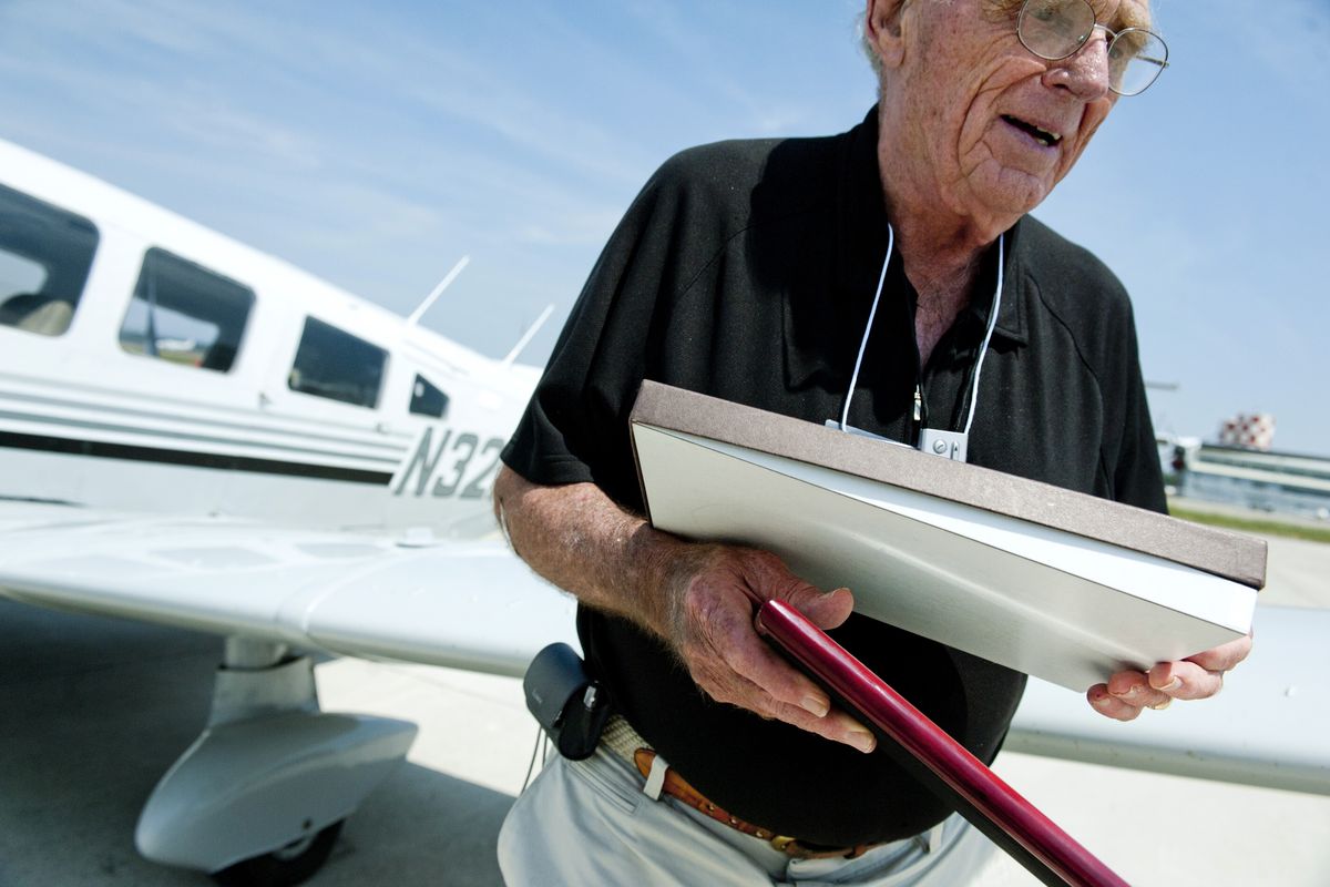 Bill Webber of the United Flying Octogenarians walks past his plane carrying the Wright Brothers Master Pilot Award which was awarded to him on Thursday at Spokane International Airport. (Tyler Tjomsland)