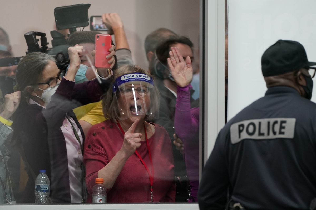 Election challengers yell as they look through the windows of the central counting board as police help to keep additional challengers from entering due to overcrowding Wednesday in Detroit.  (Associated Press)