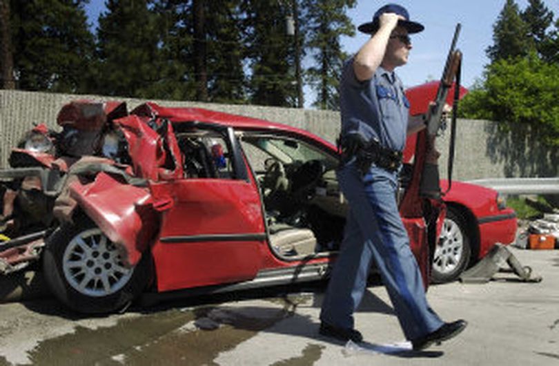 In this photo from May 2006, Washington State Patrol Sgt. Lee Slemp removes a shotgun from an unmarked patrol car that was rear-ended on I-90 near the Garden Springs exit. 
 (Colin Mulvany / The Spokesman-Review)