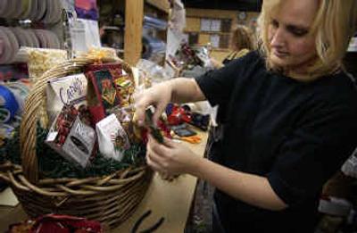 
Sharon Strine decorates a $100 office party gift basket with a poinsettia at Simply Northwest in Spokane Valley. 
 (Liz Kshimoto/ / The Spokesman-Review)