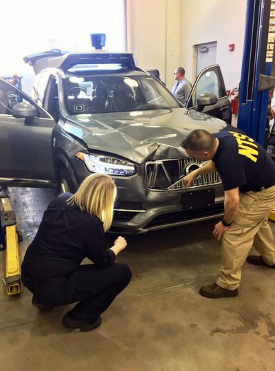 Investigators examine a driverless Uber SUV on March 20, 2018, that fatally struck a woman in Tempe, Ariz. An Arizona police report says the human backup driver the Uber autonomous SUV was streaming a television show on Hulu just before the vehicle struck and killed a pedestrian in March. (Associated Press)