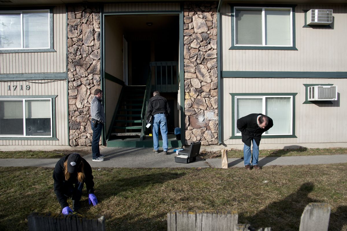 Spokane Police Department detectives and forensics members search for metal in the front area of a fourplex at 1719 N. Maple St. in Spokane where a shooting occurred early Monday. Two people were shot there, and two others were shot at First Avenue and Monroe Street downtown. Police believe both shootings were gang-related, but whether they are connected is still under investigation. (Dan Pelle)