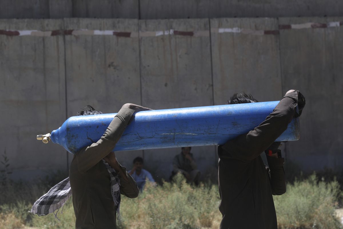 Men carry a cylinder to be refilled from a privately owned oxygen factory, in Kabul, Afghanistan, Saturday, June 19, 2021. Health officials say Afghanistan is fast running out of oxygen as a deadly third surge of COVID worsen.  (Rahmat Gul)