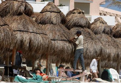 
Tourists sit in the sun as restoration work continues on an adjacent palapa in Cancun, Mexico, on Tuesday. 
 (Associated Press / The Spokesman-Review)