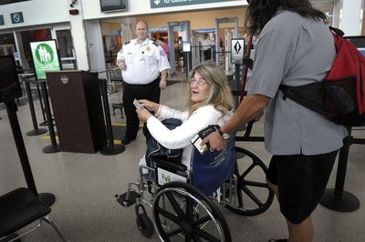 Steve Doutre pushes activist Cathy Mann through airport security Friday as she says goodbye to friends. They were among Spokane-area residents headed to Los Angeles for this weekend’s Equal Voices Convention.   (CHRISTOPHER ANDERSON / The Spokesman-Review)