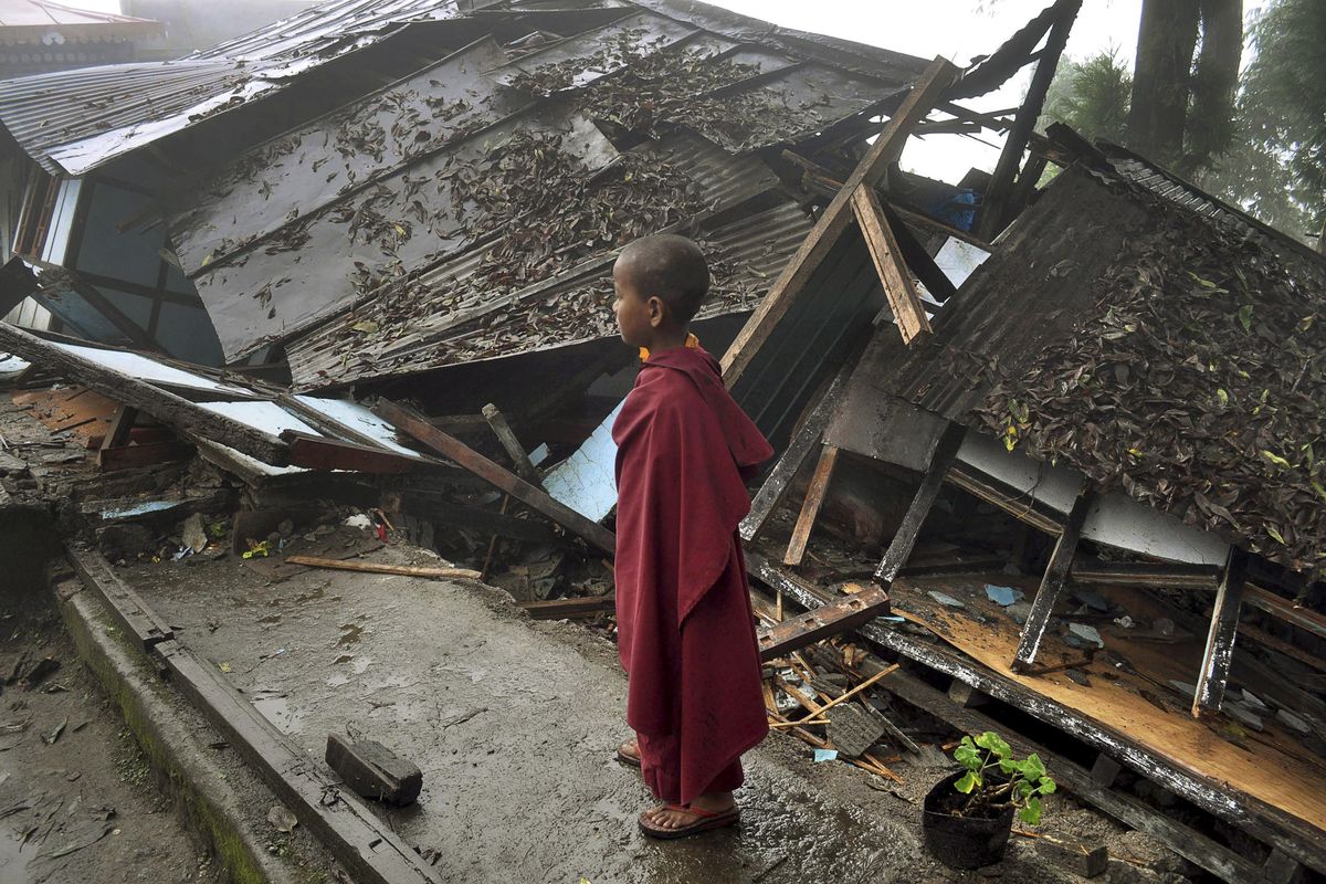 A young Buddhist monk looks on at a monastery damaged by Sunday