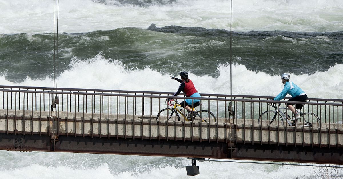 Cyclists pedal across the suspension bridge above Spokane Falls on Sunday. (Kathy Plonka)