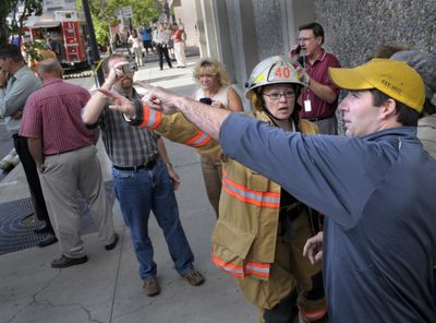 Spokane Fire Department personnel ask spectators to describe what they saw  during the three-alarm fire. (Christopher Anderson / The Spokesman-Review)