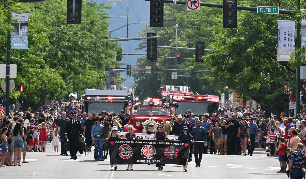 Spectators stand Friday as memorial banners, a pair of riderless horses draped in flags and an antique fire engine lead firefighters, friends and family members of the slain firefighters, who were murdered responding to a fire on nearby Canfield Mountain, at the beginning of the annual American Heroes Fourth of July Parade in Coeur d’Alene. (Jesse Tinsley/THE SPOKESMAN-REVIEW)