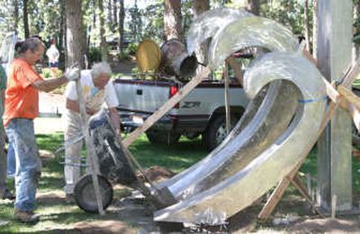 
From left, artists Allen Dodgeand Harold Balazs work on installing the sculpture 