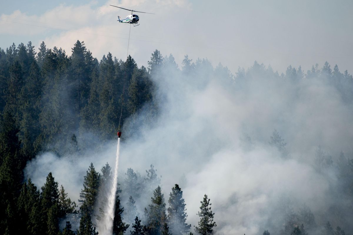 A Huey helicopter drops water while fighting a wildfire near Boulder Beach Park on Thursday, July 6, 2017, in Spokane, Wash. (Tyler Tjomsland / The Spokesman-Review)