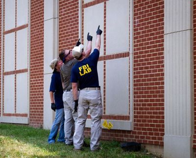 Crime scene investigation members look at what appears to be a bullet hole on a building across the street from the baseball field in Alexandria, Va., Wednesday, June 14, 2017, where House Majority Whip Steve Scalise of La., and others, were shot during a Congressional baseball practice. (AP Photo/Cliff Owen)