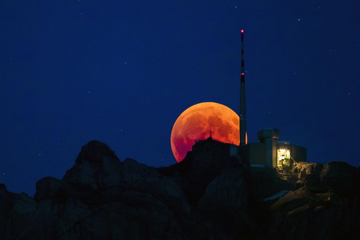 The moon turns red during a total lunar eclipse, behind the Saentis in Luzern, Switzerland, Friday, July 27, 2018. Skywatchers around much of the world are looking forward to a complete lunar eclipse that will be the longest this century. (Christian Merz/Keystone / Associated Press)