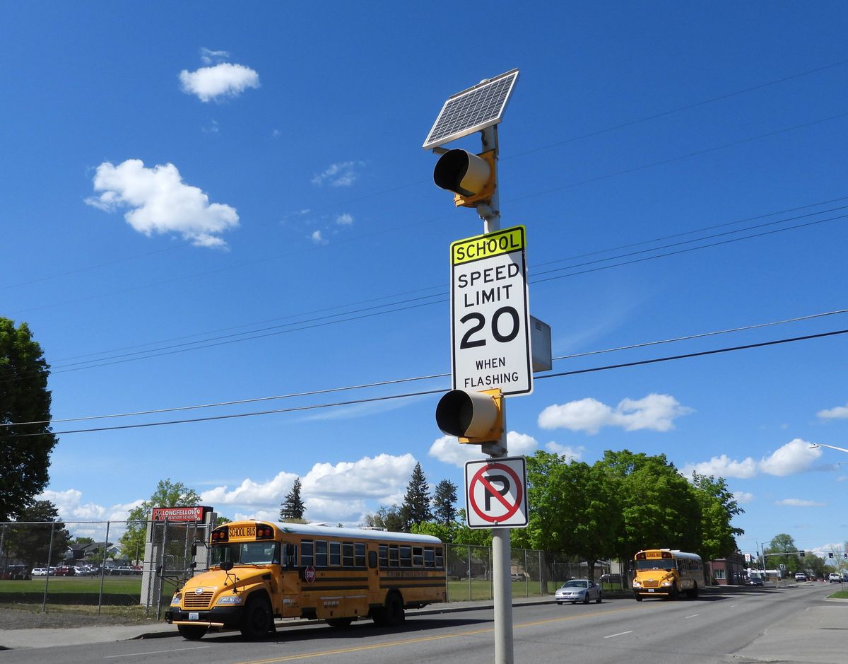 A set of flashing lights and a speed limit sign warns drivers that the area of North Nevada Street is a 20 mph school zone during certain hours of the day, as seen in this May 2021 photo. Classes begin Tuesday at Spokane Public Schools, and officials are warning both motorists and pedestrians to obey all traffic laws.  (Jesse Tinsley/The Spokesman-Review)