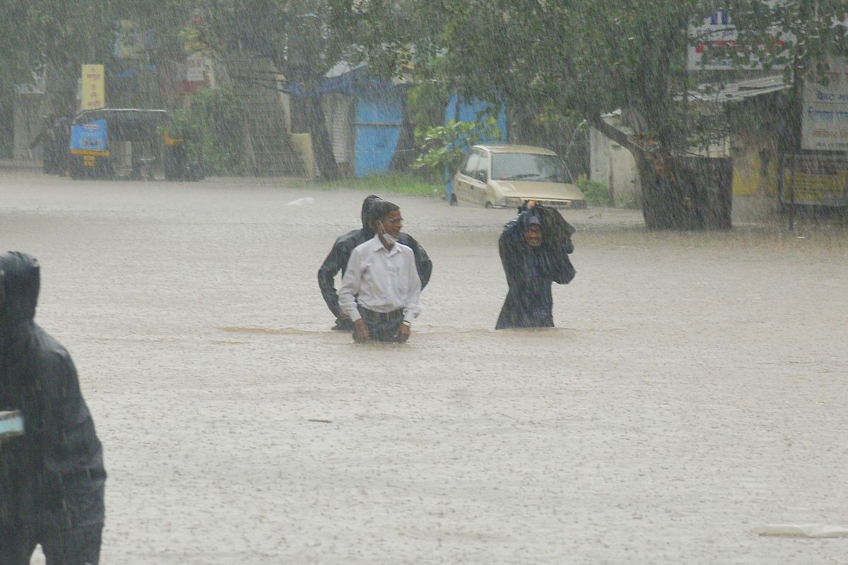 People wade through floodwaters in Kolhapur, in the western Indian state of Maharashtra, Friday, July 23, 2021. Landslides triggered by heavy monsoon rains hit parts of western India, killing more than 30 people and leading to the overnight rescue of more than 1,000 other people trapped by floodwaters, officials said Friday.  (STR)