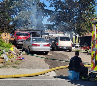 Firefighters with the Spokane Valley Fire Department rest in the shade after extinguishing a two-alarm fire that destroyed a recreational vehicle and a garage in Spokane Valley Tuesday afternoon.   (Nick Gibson/The Spokesman-Review)