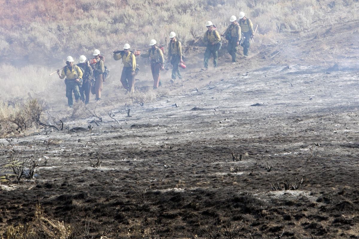 A team of Hotshots walk along a fire line near homes on Croy Road and the Rotorun ski hill west of Hailey on Saturday. (Associated Press)