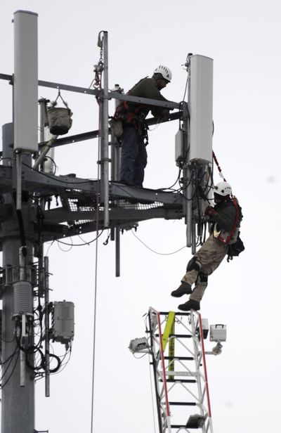 A cell tower worker, right, balances on the end of a fire department ladder Sunday afternoon after he slipped off the tower platform and his fellow worker, left, held on to part of the safety rigging as the man dangled until the fire department could put up the ladder. A technical rescue firefighter brought the man down safely. (Jesse Tinsley)