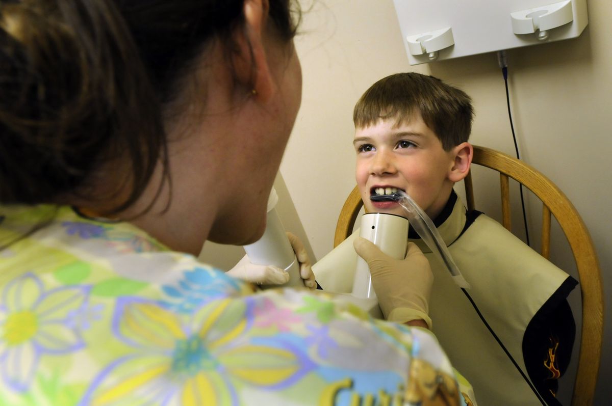 Dental assistant Robin Adkison prepares 8-year-old Tanner Slauson for a digital X-ray during a checkup at Dr. Christopher Herzog’s office Tuesday. (Photos by Jesse Tinsley / The Spokesman-Review)