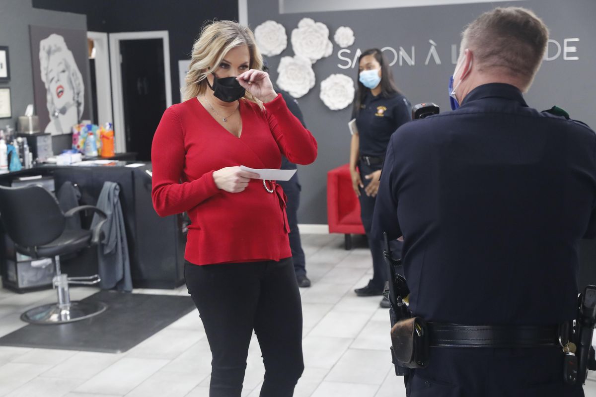 Salon owner Shelley Luther holds a citation and speaks with a Dallas police officer after she was cited for reopening her Salon A la Mode in Dallas, Friday, April 24, 2020. Hair salons have not been cleared for reopening in Texas. (LM Otero / Associated Press)