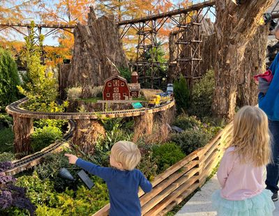 The holiday train display at the U.S. Botanic Garden in Washington, D.C., has a farming theme for 2021. A family looks at the display, which is outdoors this year.  (U.S. Botanic Garden)