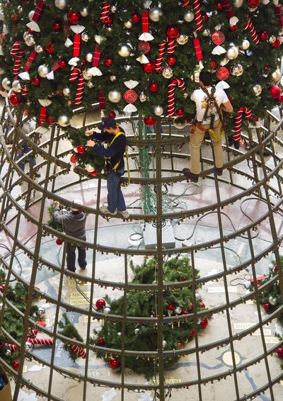 Up a tree: Spokane city firefighters Marlin Thorman, left, and Steve Harms, volunteering through Spokane Firefighters IAFF Local 29, help install 689 branches on the 50-foot Christmas tree in River Park Square on Thursday. The tree has 10,000 lights and approximately 2,700 ornaments. Santa is scheduled to arrive Nov. 22 at 7p.m. (Colin Mulvany)