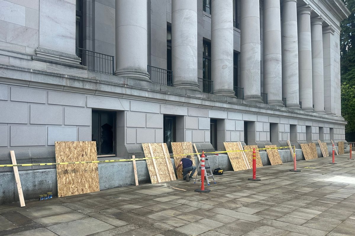 Crews are seen boarding up broken windows at the State Capitol in Olympia following a vandalism incident on Thursday.  (Mitchell Roland/THE SPOKESMAN-REVIEW)