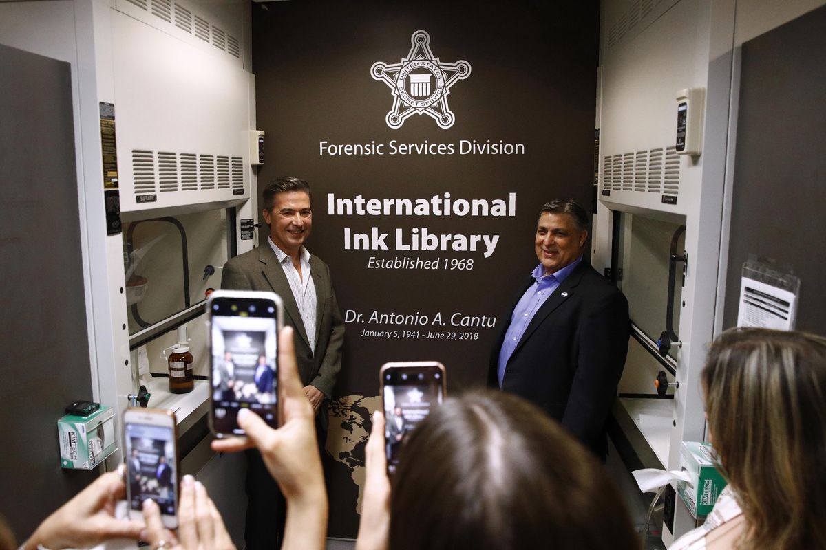In this June 27, 2019 photo, Vidal Cantu, left, and Arnold Cantu pose for photos in the International Ink Library, which was dedicated in remembrance of their uncle, former U.S. Secret Service chief chemist Antonio Cantu, during a visit to the Secret Service headquarters building in Washington. (Patrick Semansky / AP)