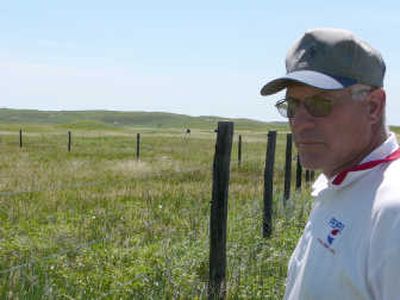 
Rancher Duane Kime stands near a fence that separates billionaire Ted Turner's land from his in Mullen, Neb., in June. Over the past decade, Kime has watched the tall, industrial-strength livestock fences Turner prefers for holding in his buffalo surround about three-quarters of his property, and more are on the way. Like others in the area, Kime is concerned about what plans Turner, the largest landowner in Nebraska and the U.S., has for the land he is accumulating. Associated Press file photos
 (Associated Press file photo / The Spokesman-Review)